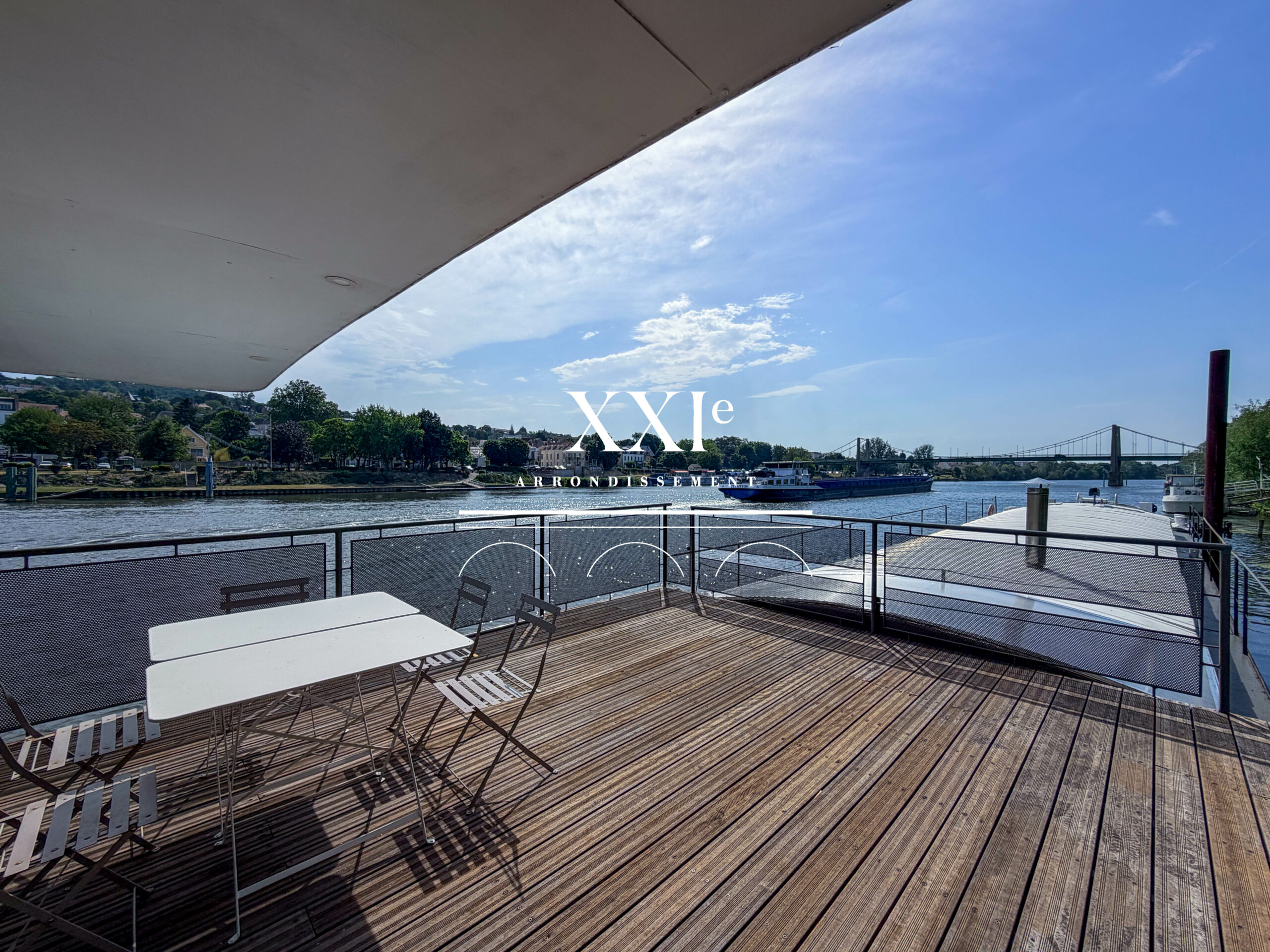 Terrasse d'une péniche d'habitation à Triel-sur-Seine avec vue dégagée sur la Seine, jardin privatif et environnement verdoyant
